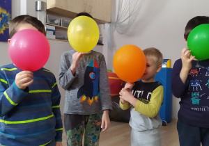 Dzieci zasłaniają buzie balonami